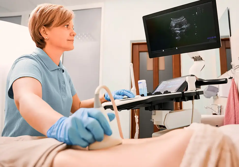 Woman performing ultrasound therapy on a patient’s leg with monitoring screen displaying ultrasound image, emphasizing pain relief and healing at Savannah Pelvic Health and Wellness in Pooler.