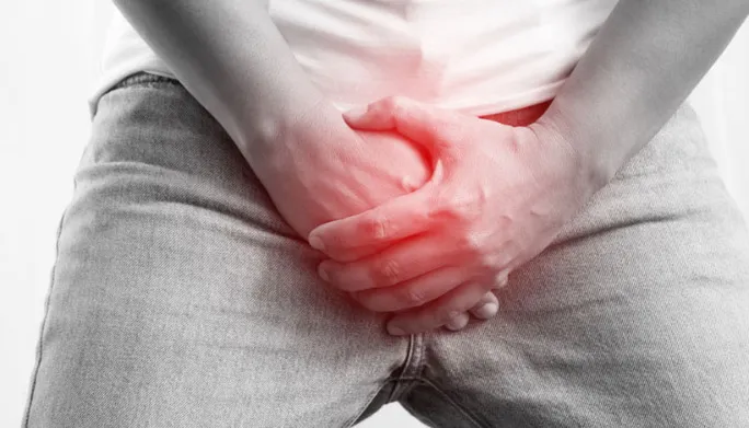 Man holding his groin in discomfort, illustrating testicular pain related to pelvic floor health.